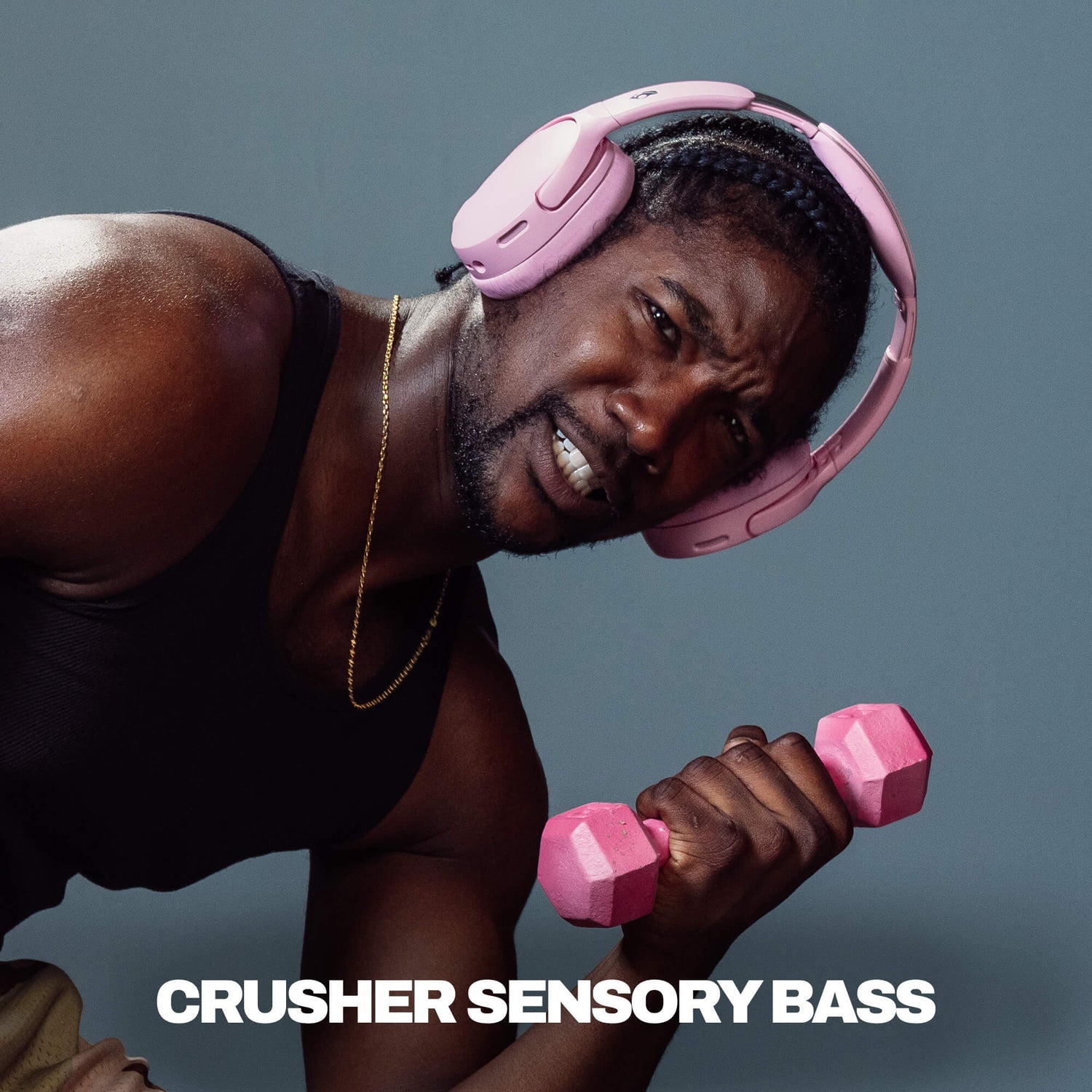 Man wearing pink Crusher 1080 and holding pink dumbbells with text 'CRUSHER SENSORY BASS' on a gray background | Candy