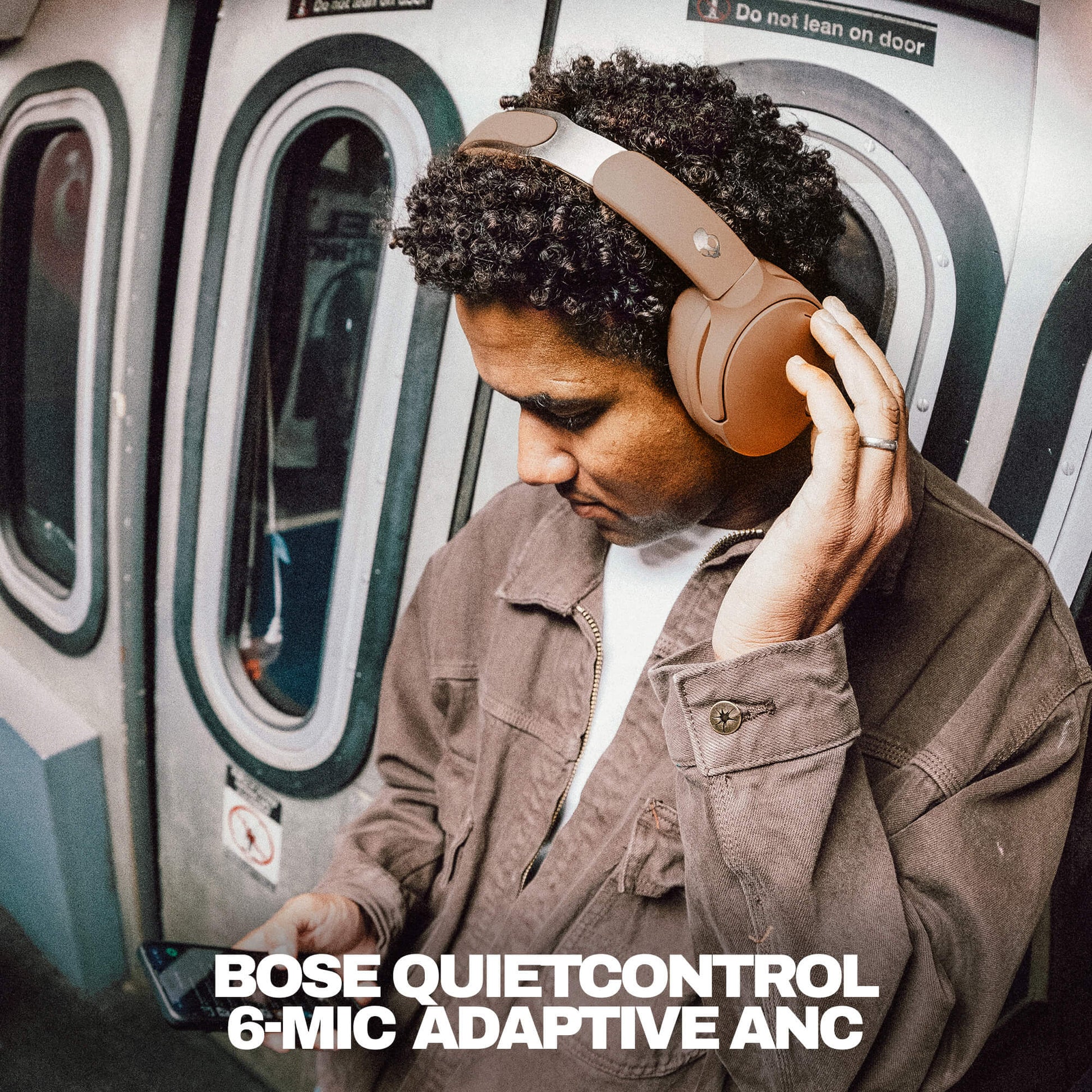 Person wearing Skullcandy crusher 1080 with Bose QuietControl headphones on a subway train, with product name displayed. | Primer