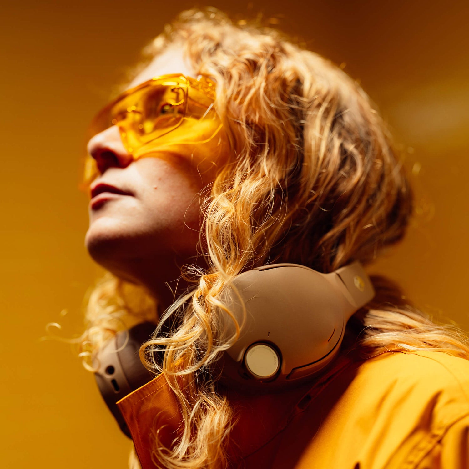 Person wearing yellow sunglasses and headphones against a warm-toned background | Primer