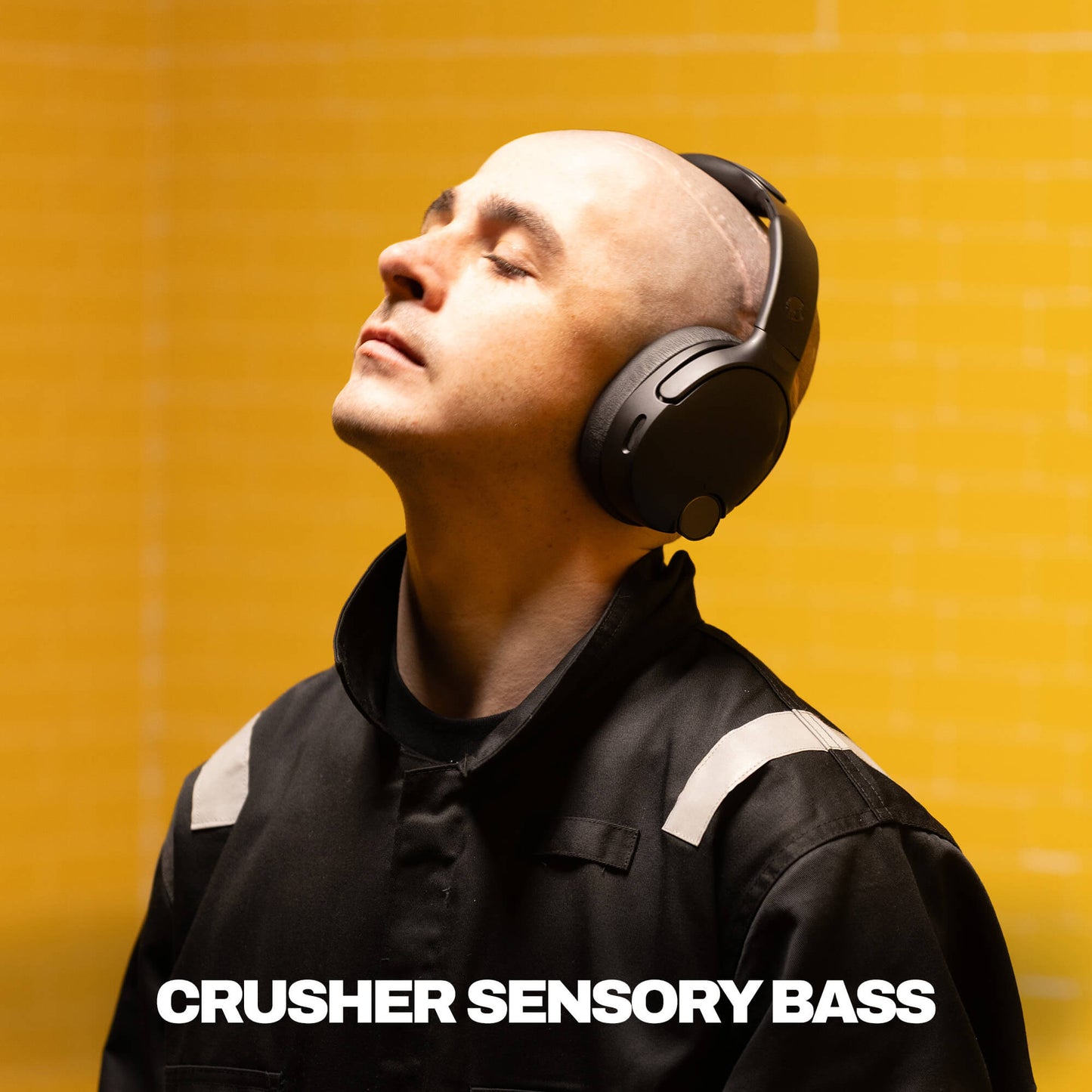 Man wearing Crusher 1080 ANC with 'Crusher Sensory Bass' text on a yellow background | True Black