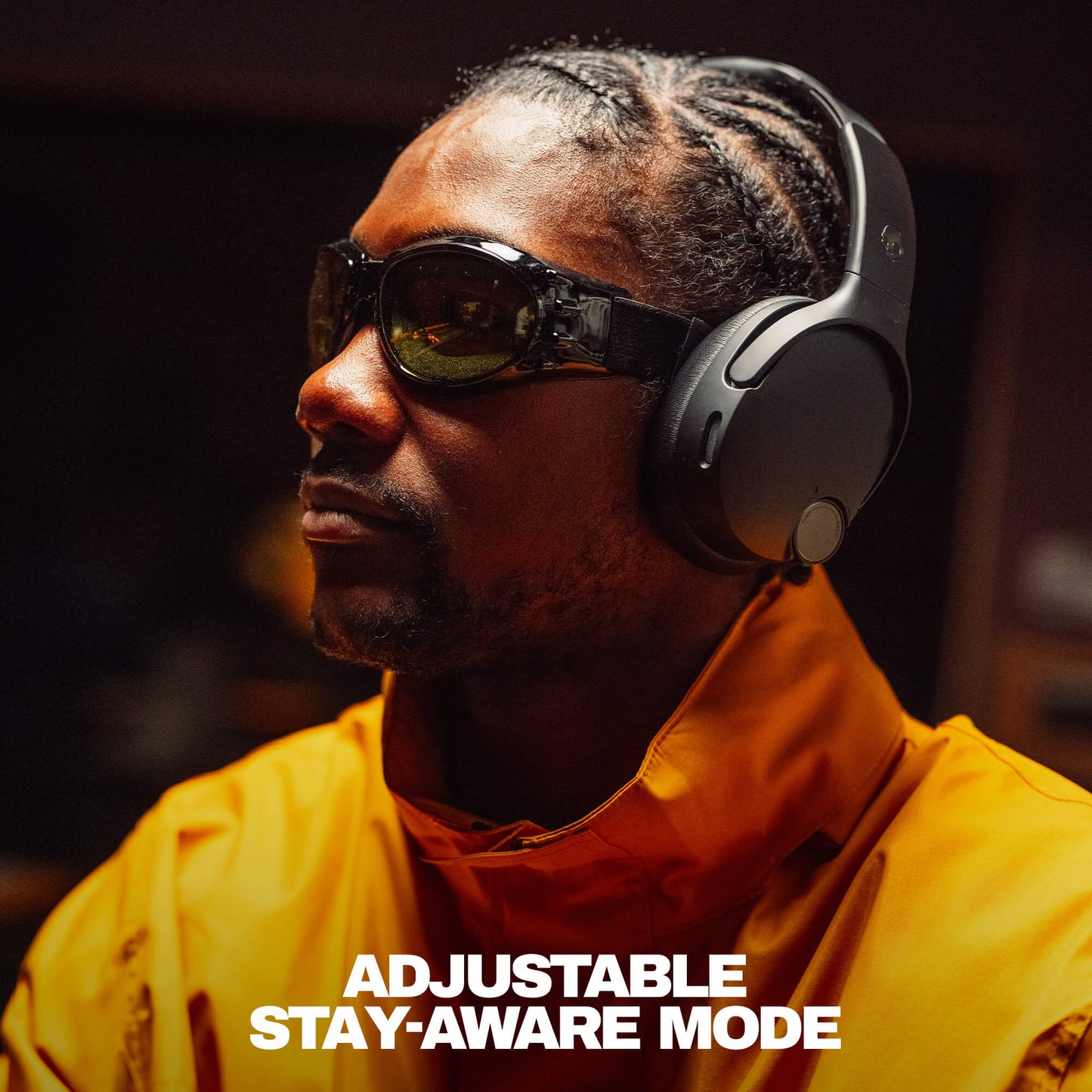 Person wearing sunglasses and headphones with text 'Adjustable Stay-Aware Mode' on a dark background | True Black