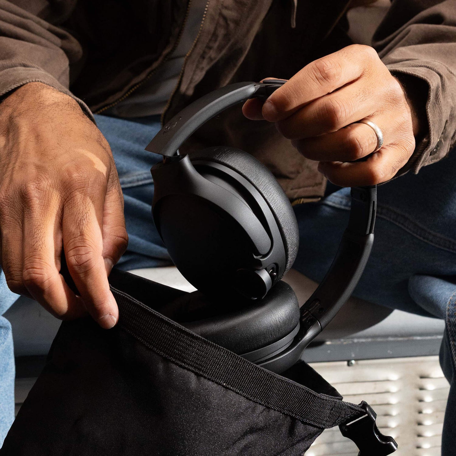 Person holding a pair of black crusher 1080 ANC  with a focus on the hands and product.