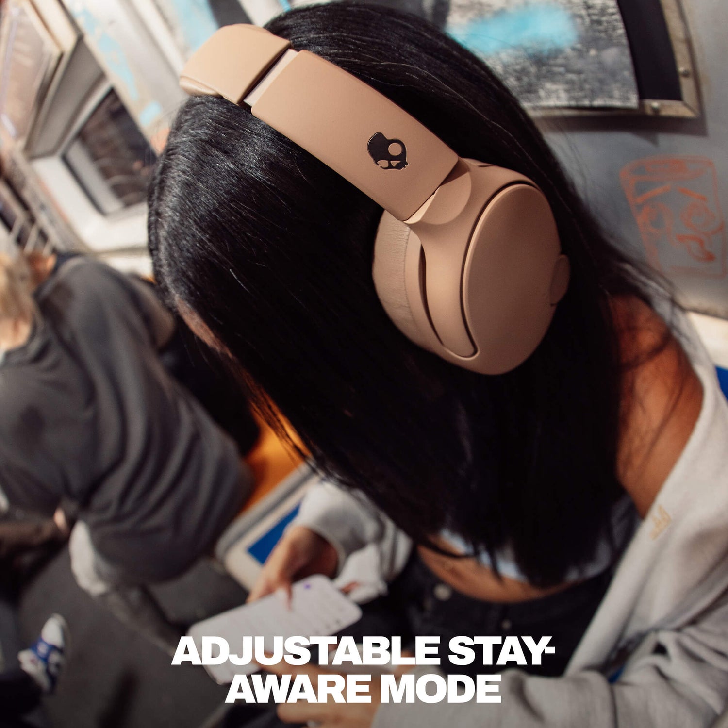 Person wearing gold Crusher 720 headphones on a plane with text 'Adjustable Stay Aware Mode'. | Primer
