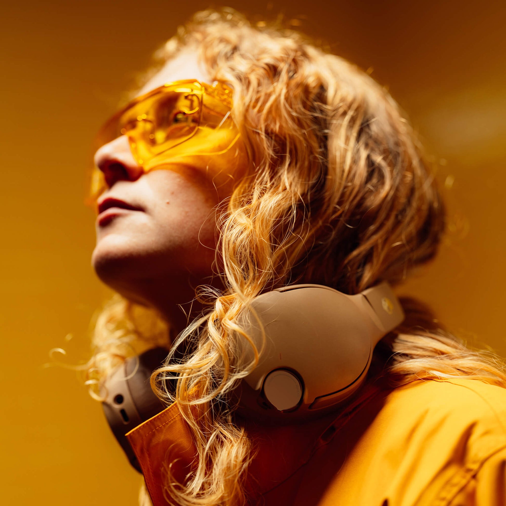 Person wearing yellow sunglasses and the Crusher 720 headphones against an orange background | Primer