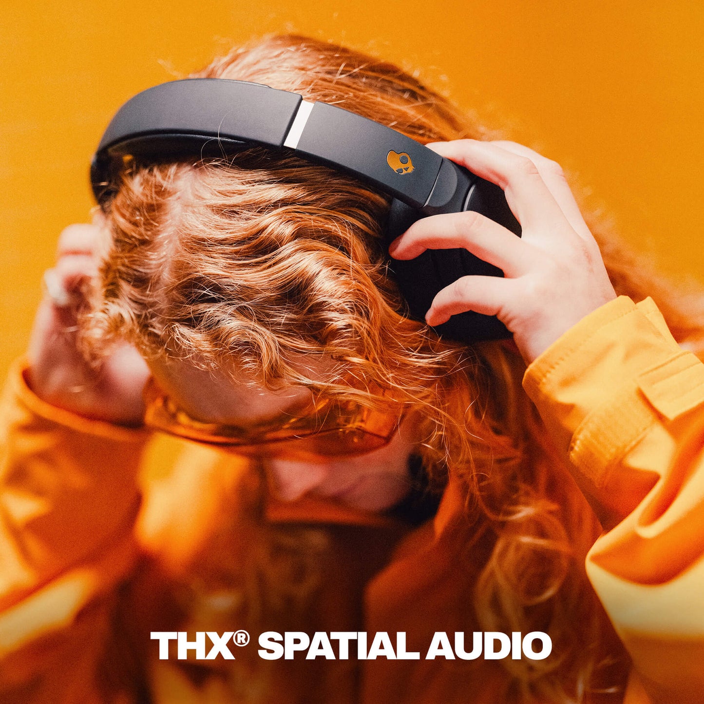Person wearing black Crusher 720 with THX Spatial Audio branding against an orange background | True Black