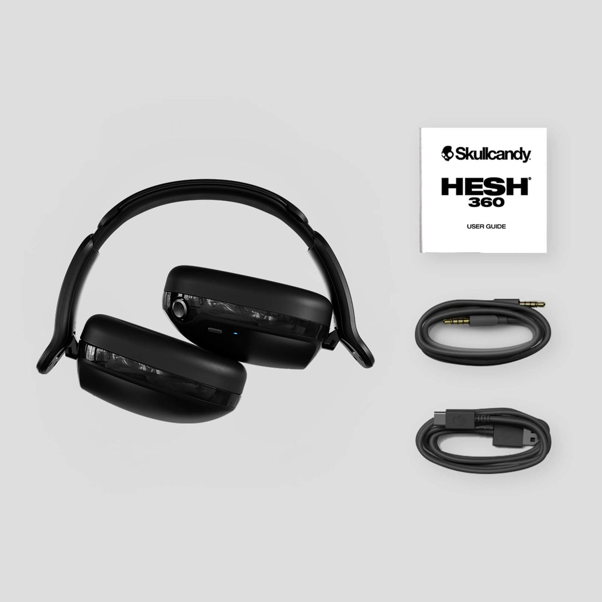 Black headphones with cables and Skullcandy HESH 360 user guide on a light gray background | Future