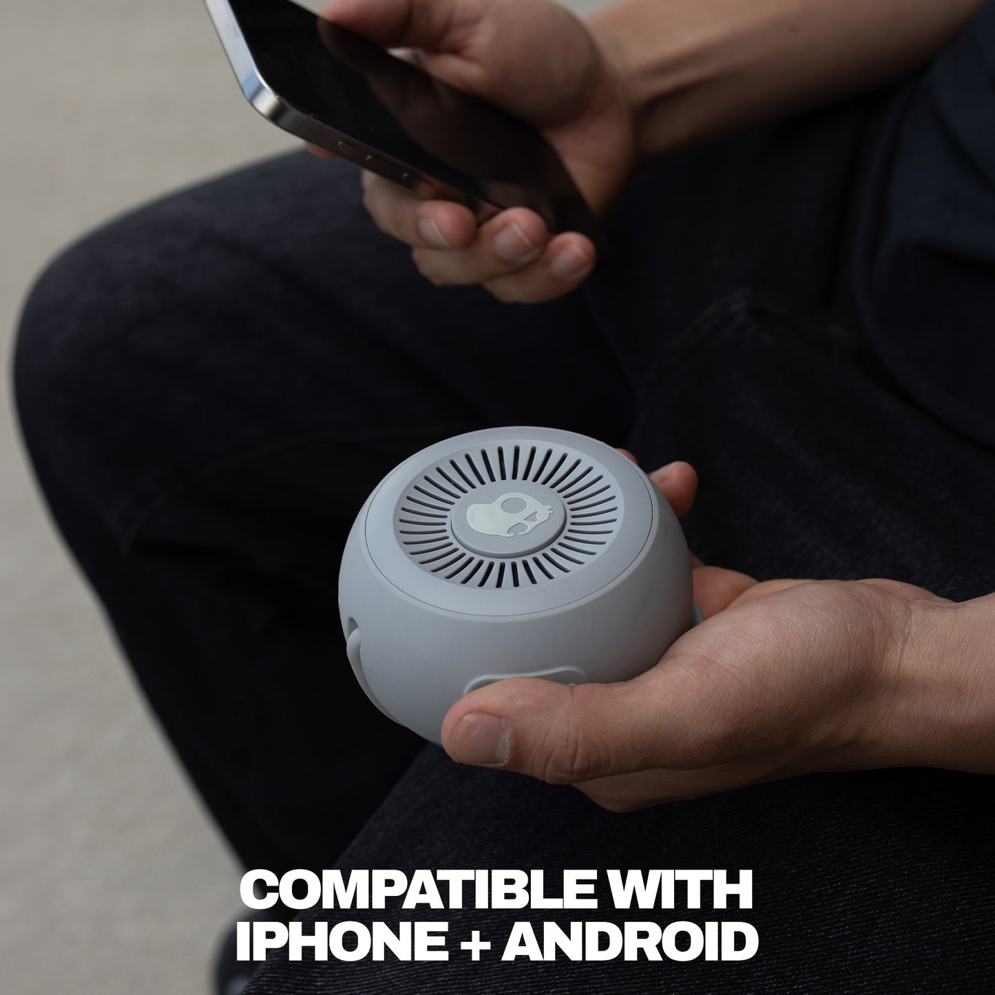 Person holding a small speaker with text indicating compatibility with iPhone and Android. | Cement