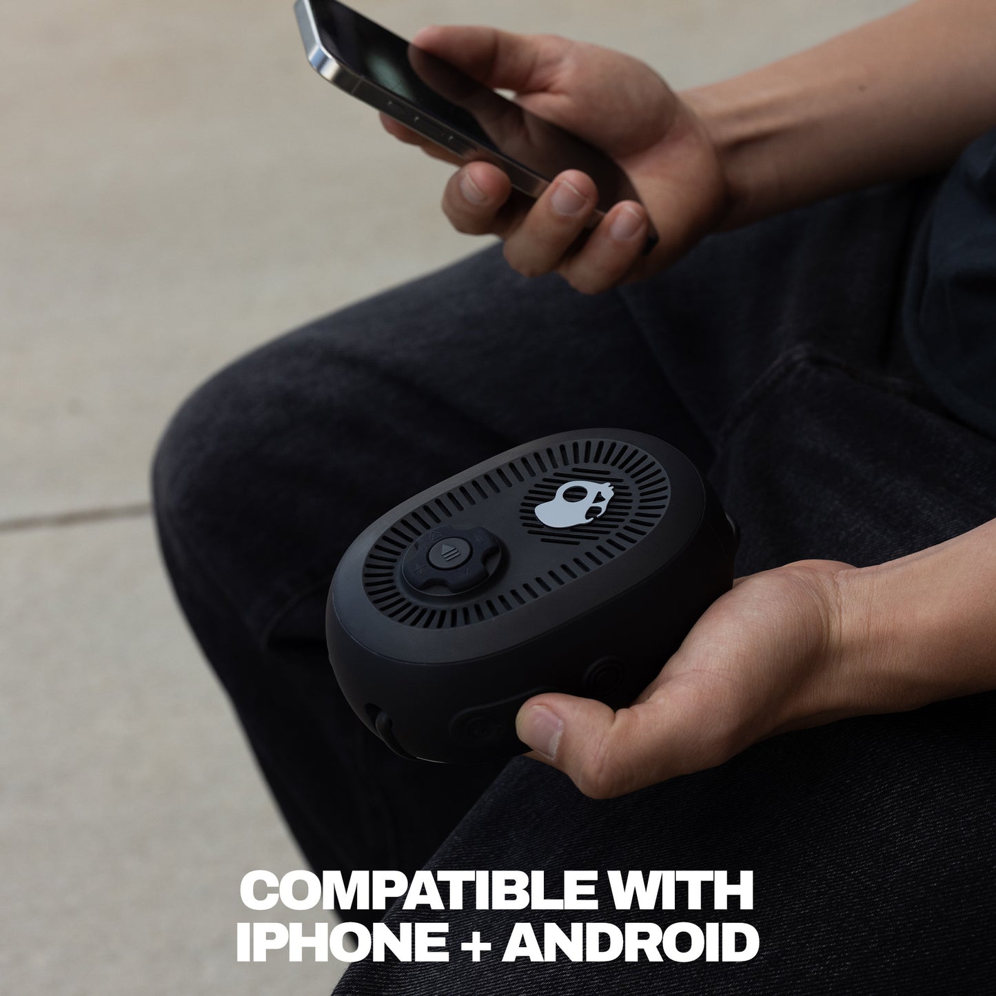 Person holding a speaker with a smartphone, text 'Compatible with iPhone + Android' on a neutral background | True Black