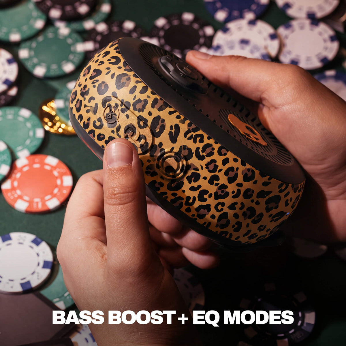 A person's hands holding a session 540 portable speaker with a tan and black leopard print pattern, set against a background of playing cards and poker chips with the text 'BASS BOOST + EQ MODES' at the bottom. | Leopard