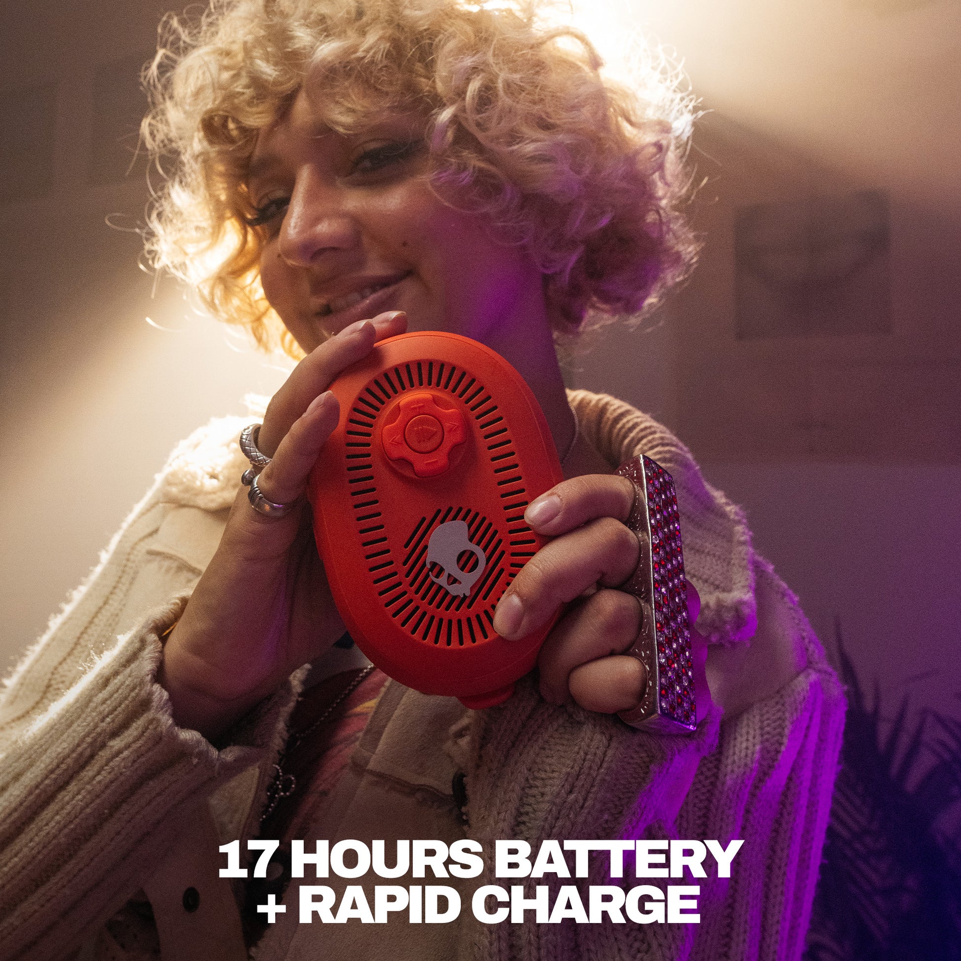 Person holding a red speaker with text about battery life and charging speed. | Plasma