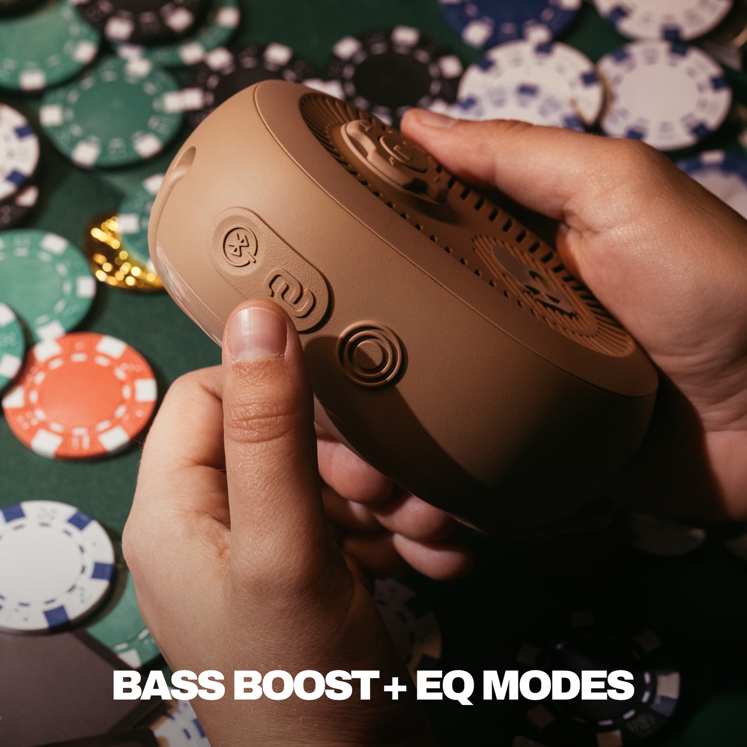 Hand holding a brown speaker with poker chips in the background | Primer