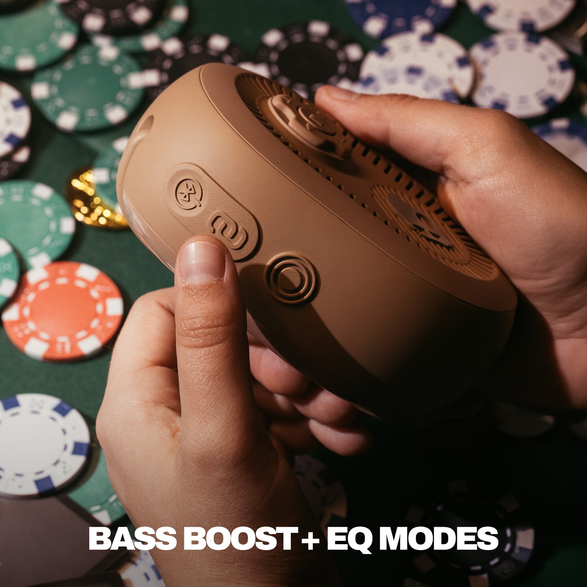 Hand holding a brown speaker with poker chips in the background | Primer
